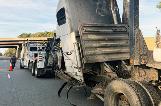 Damaged semi truck being hooked up to heavy duty tow truck in Warsaw NC near US-117